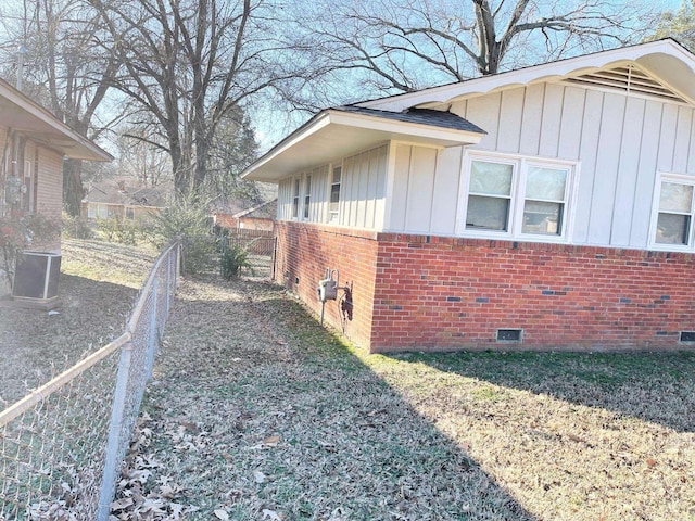 view of property exterior featuring crawl space, brick siding, board and batten siding, and fence