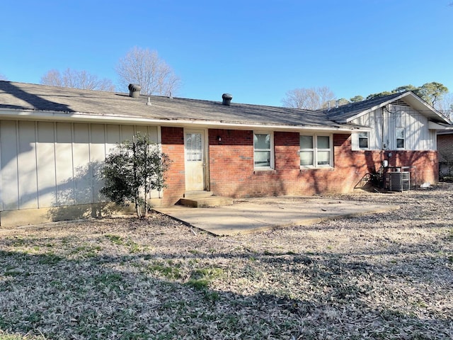 rear view of property featuring cooling unit, brick siding, board and batten siding, and entry steps