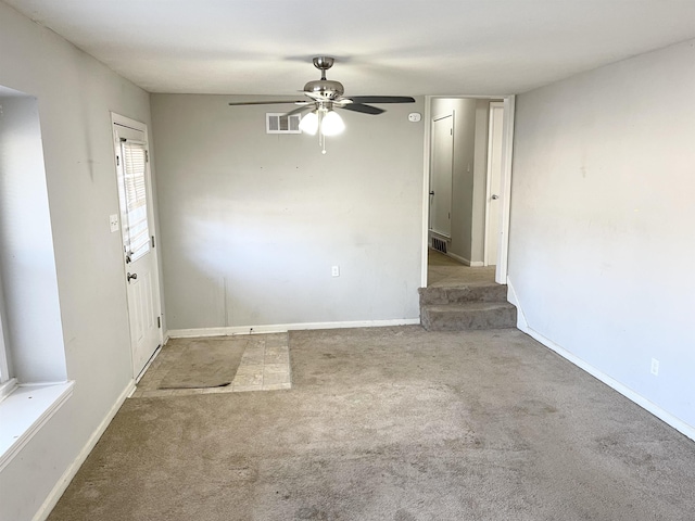 carpeted empty room with baseboards, visible vents, and ceiling fan