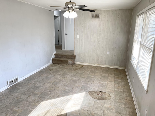 empty room with visible vents, baseboards, ceiling fan, and stairway