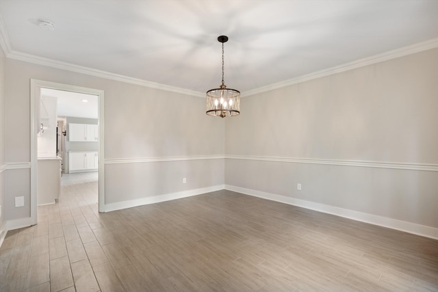 spare room featuring a notable chandelier, wood finished floors, baseboards, and ornamental molding