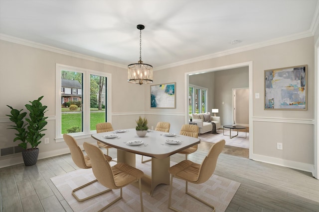 dining area with baseboards, light wood-type flooring, an inviting chandelier, and ornamental molding