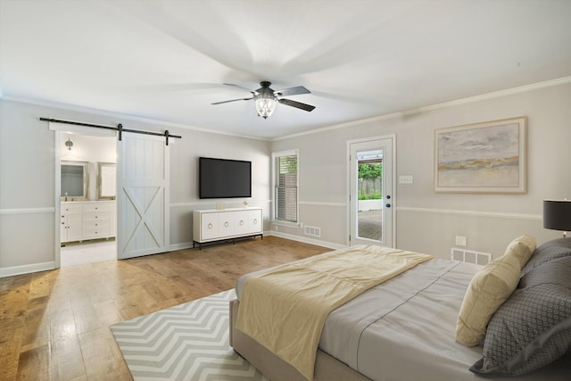 bedroom featuring visible vents, baseboards, a barn door, ornamental molding, and wood finished floors