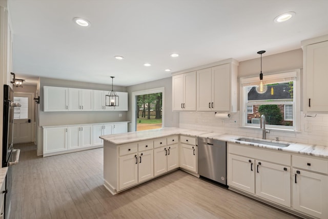 kitchen featuring light wood-type flooring, a sink, tasteful backsplash, stainless steel appliances, and a peninsula