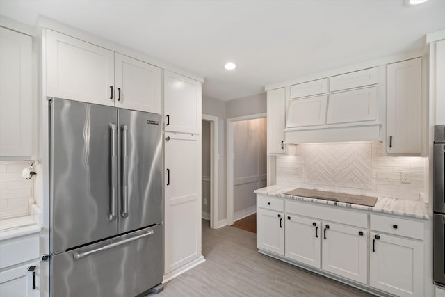 kitchen featuring backsplash, white cabinets, high quality fridge, and black electric stovetop