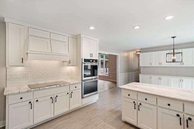 kitchen featuring tasteful backsplash, white cabinetry, double oven, light wood finished floors, and black electric cooktop