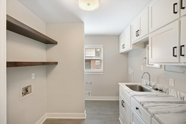 laundry area featuring washer hookup, a sink, wood finished floors, cabinet space, and baseboards