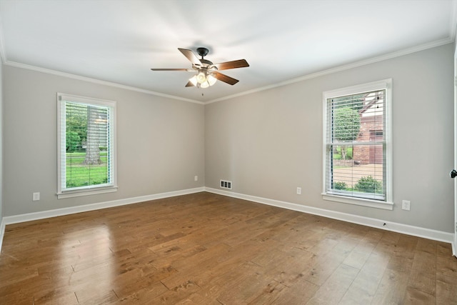 unfurnished room with visible vents, a healthy amount of sunlight, dark wood-type flooring, and ornamental molding