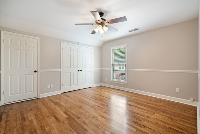 unfurnished bedroom featuring wood finished floors, visible vents, baseboards, lofted ceiling, and ceiling fan