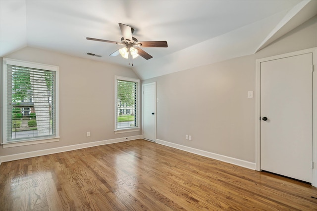 spare room featuring baseboards, visible vents, ceiling fan, vaulted ceiling, and light wood-type flooring