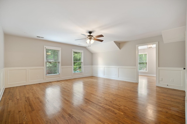 spare room featuring visible vents, lofted ceiling, light wood-style flooring, and ceiling fan with notable chandelier