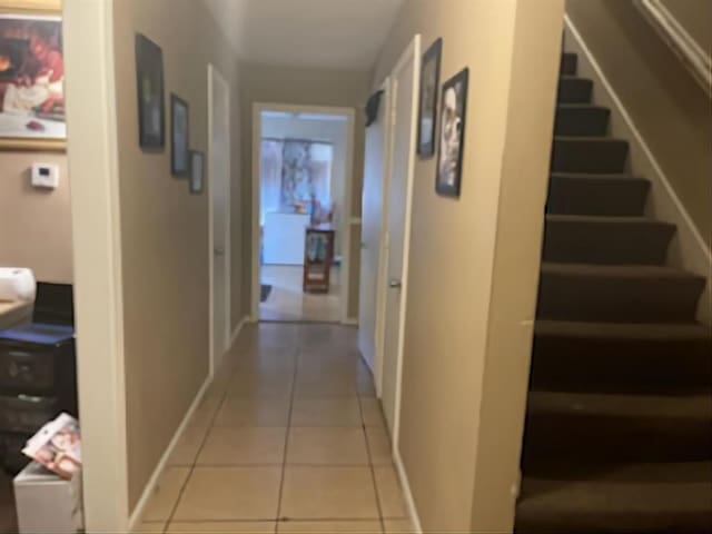 hall featuring stairway, light tile patterned flooring, and baseboards