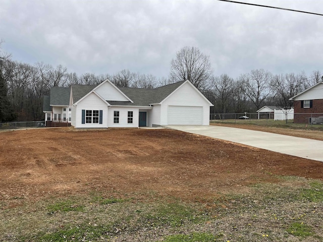 view of front of home with a garage, concrete driveway, a front lawn, and fence