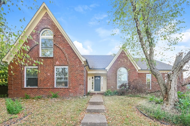 view of front facade with brick siding, a shingled roof, and a front lawn