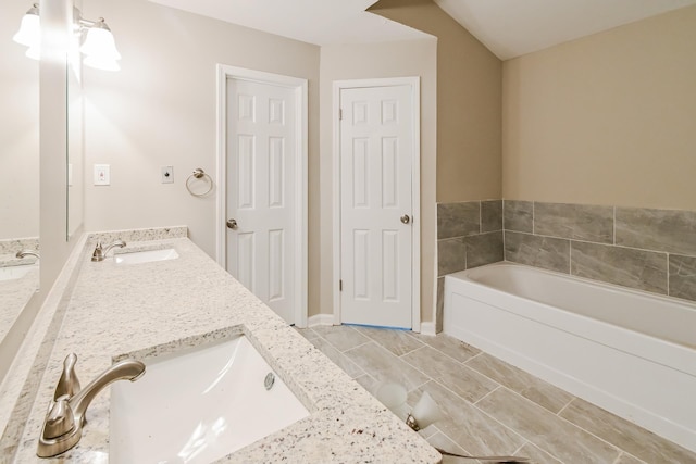 full bath with a bath, double vanity, and a sink