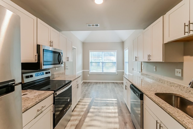 kitchen featuring visible vents, a sink, white cabinetry, stainless steel appliances, and light wood-style floors