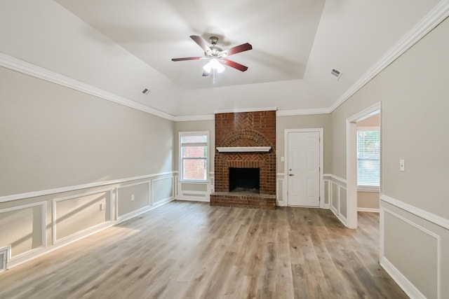 unfurnished living room with visible vents, a ceiling fan, a tray ceiling, wood finished floors, and a fireplace