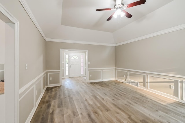 spare room with a raised ceiling, wood finished floors, crown molding, and a decorative wall