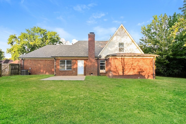 rear view of house with a patio, fence, a yard, brick siding, and a chimney