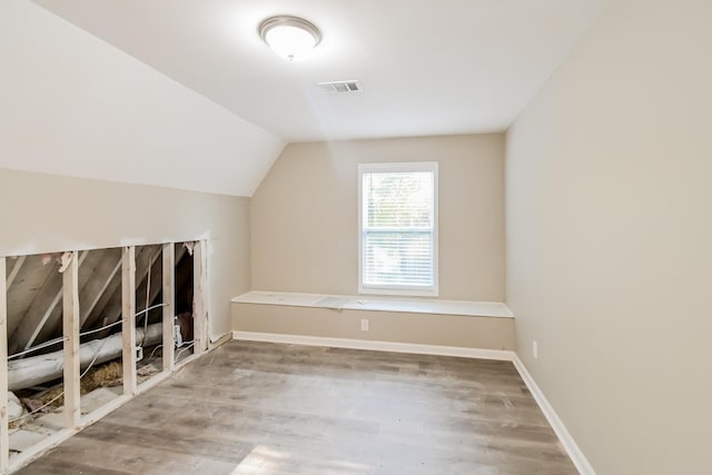 additional living space with visible vents, baseboards, wood finished floors, and vaulted ceiling