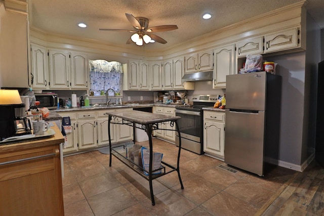 kitchen with ceiling fan, a sink, under cabinet range hood, a textured ceiling, and appliances with stainless steel finishes