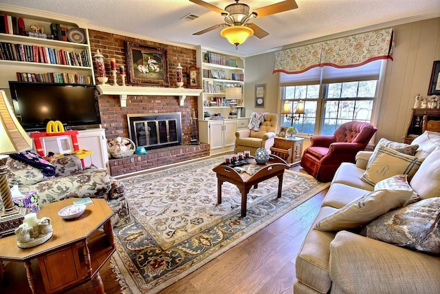 living room featuring visible vents, ornamental molding, a textured ceiling, and wood finished floors