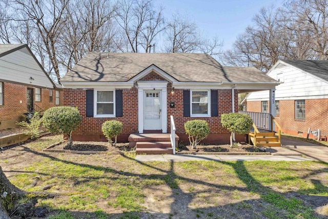 bungalow featuring brick siding, a front lawn, and a shingled roof