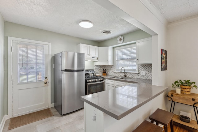 kitchen with visible vents, under cabinet range hood, appliances with stainless steel finishes, a peninsula, and a sink