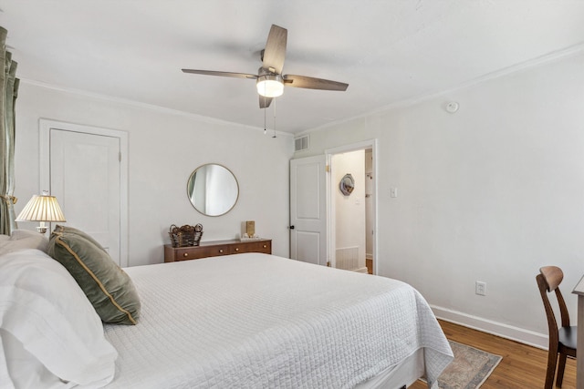 bedroom with visible vents, baseboards, ornamental molding, wood finished floors, and a ceiling fan