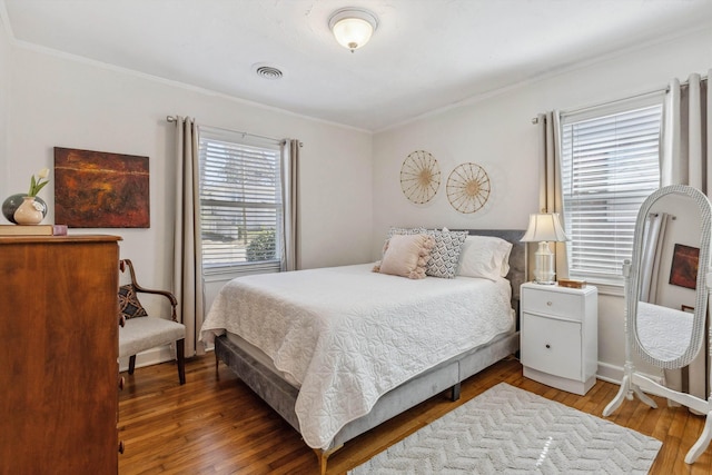 bedroom featuring visible vents, wood-type flooring, and ornamental molding