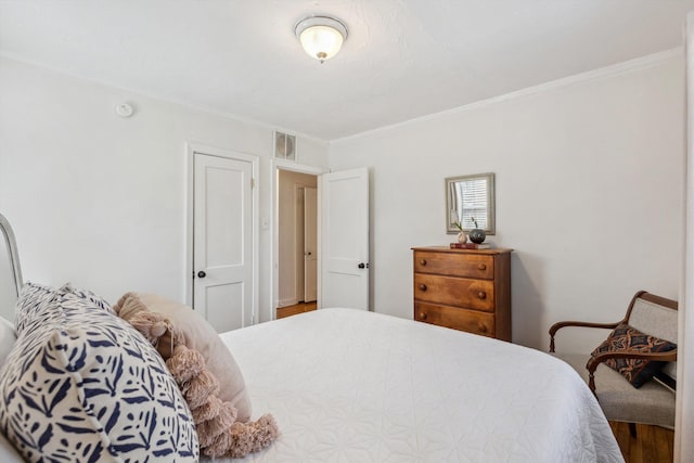 bedroom with visible vents, wood finished floors, and ornamental molding