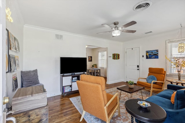 living area featuring visible vents, wood finished floors, and crown molding