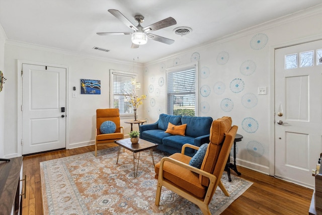 living area with visible vents, ornamental molding, baseboards, and wood finished floors