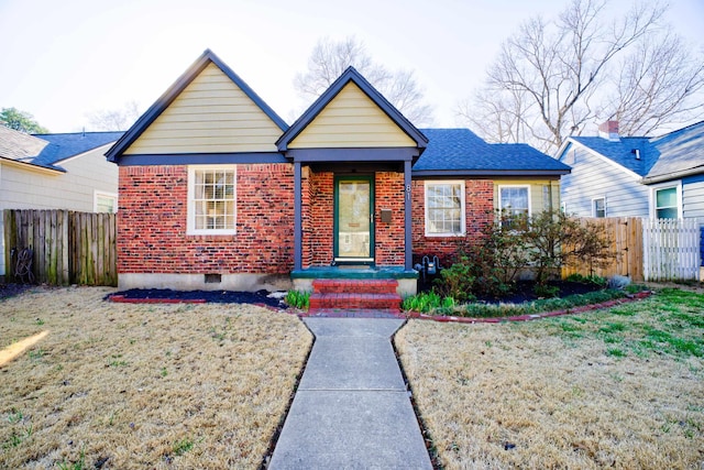 bungalow-style home with brick siding, crawl space, a front yard, and fence