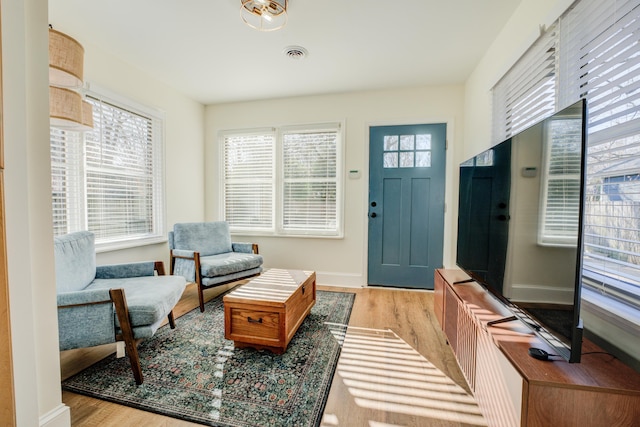 entryway with baseboards, wood finished floors, visible vents, and a healthy amount of sunlight