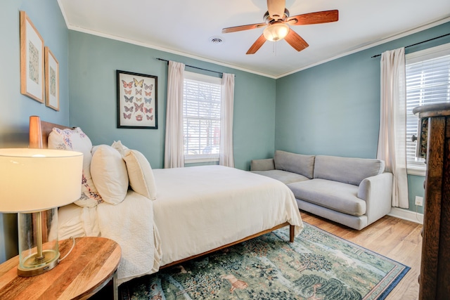 bedroom featuring visible vents, crown molding, baseboards, ceiling fan, and wood finished floors