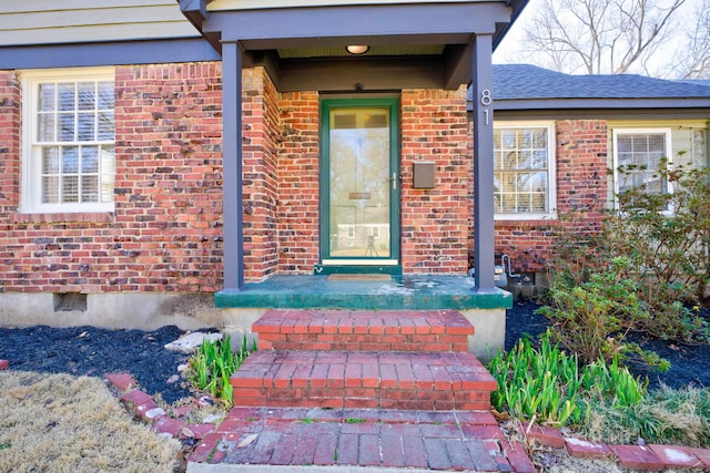 doorway to property featuring crawl space, brick siding, and roof with shingles