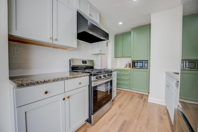 kitchen with under cabinet range hood, green cabinetry, light wood-type flooring, and appliances with stainless steel finishes