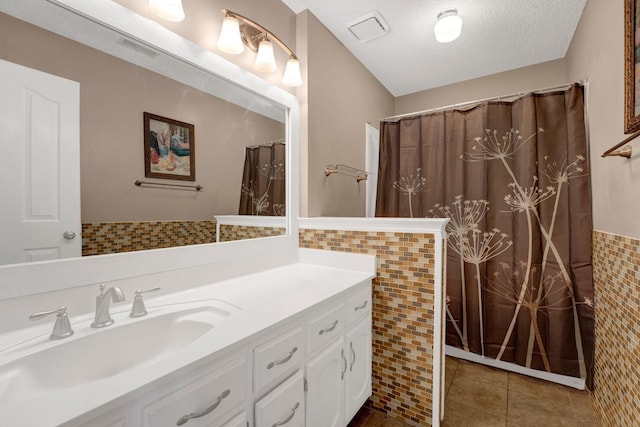 bathroom with tile walls, visible vents, tile patterned floors, and a textured ceiling