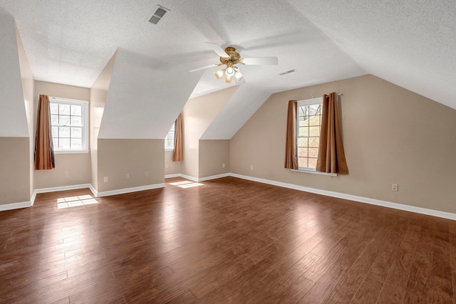 bonus room featuring baseboards, a textured ceiling, ceiling fan, and dark wood-style flooring