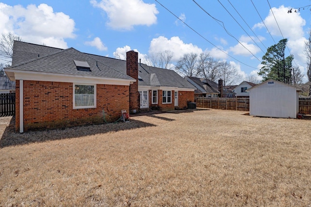 rear view of property featuring brick siding, a chimney, a yard, and fence