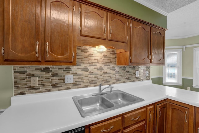 kitchen with backsplash, light countertops, ornamental molding, a textured ceiling, and a sink