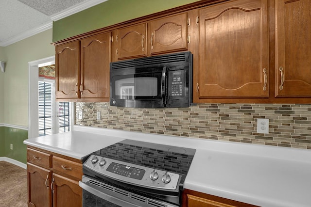 kitchen with ornamental molding, a textured ceiling, stainless steel range with electric cooktop, black microwave, and light countertops