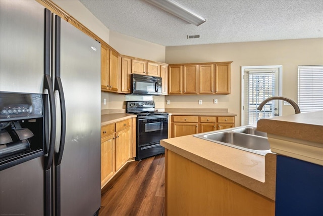 kitchen with visible vents, dark wood-type flooring, black appliances, a sink, and light countertops