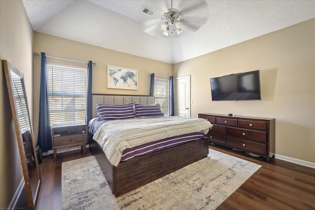 bedroom featuring wood finished floors, visible vents, baseboards, lofted ceiling, and a textured ceiling