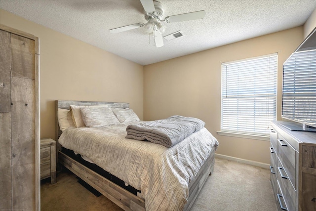 bedroom featuring a ceiling fan, baseboards, visible vents, a textured ceiling, and light colored carpet