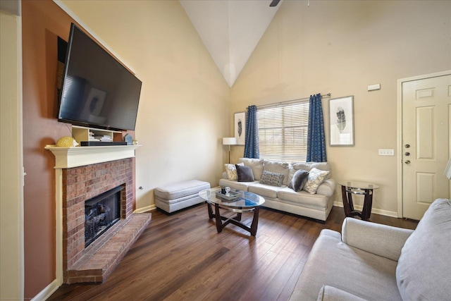 living area featuring a brick fireplace, wood finished floors, baseboards, and high vaulted ceiling