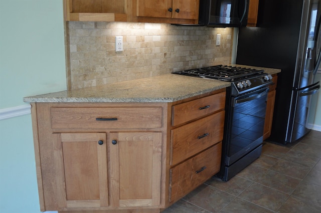 kitchen with black microwave, light stone counters, decorative backsplash, refrigerator with ice dispenser, and gas stove