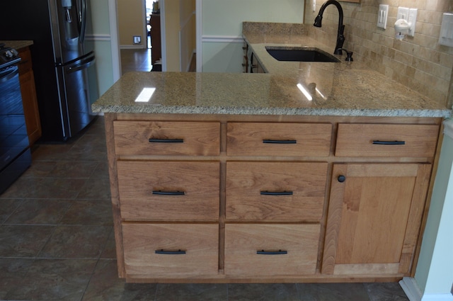 kitchen featuring light stone counters, freestanding refrigerator, a sink, range, and tasteful backsplash