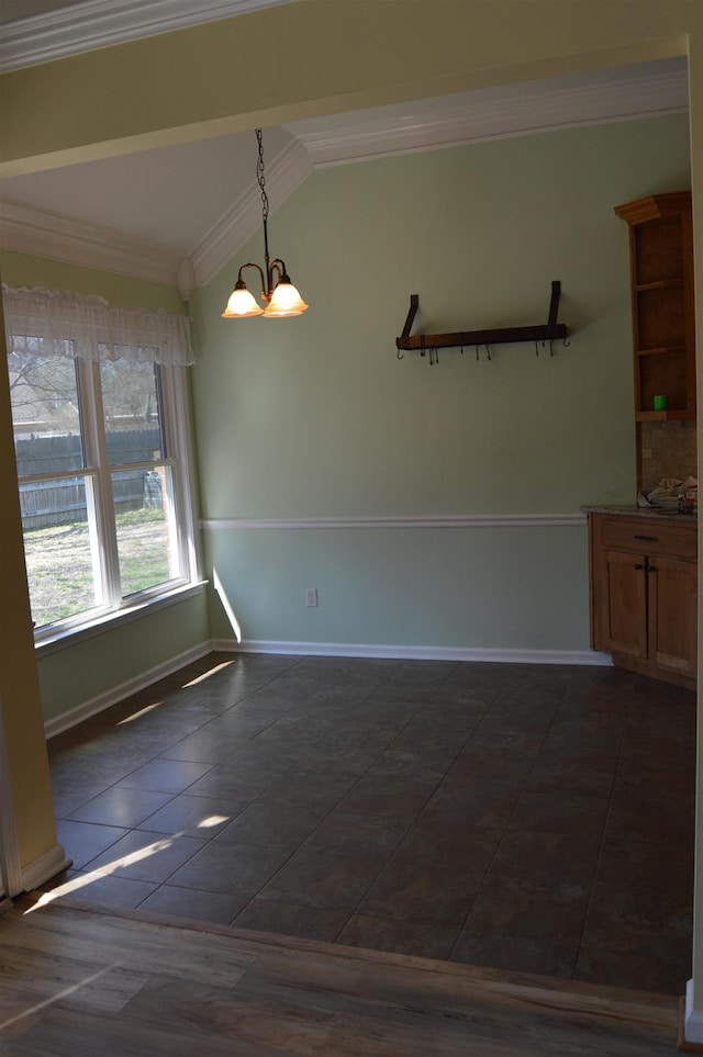 unfurnished dining area featuring baseboards, an inviting chandelier, ornamental molding, vaulted ceiling, and dark tile patterned floors